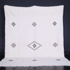 Moroccan man holding or standing near a white 6.2 x 9.2 FT flat woven Berber kilim rug
