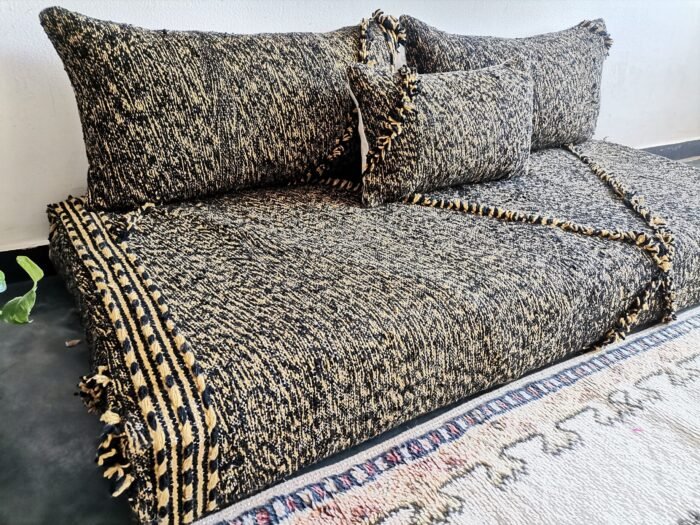 Left view of handwoven Moroccan floor couch in black and mustard – perfect for edgy, warm-toned home styling