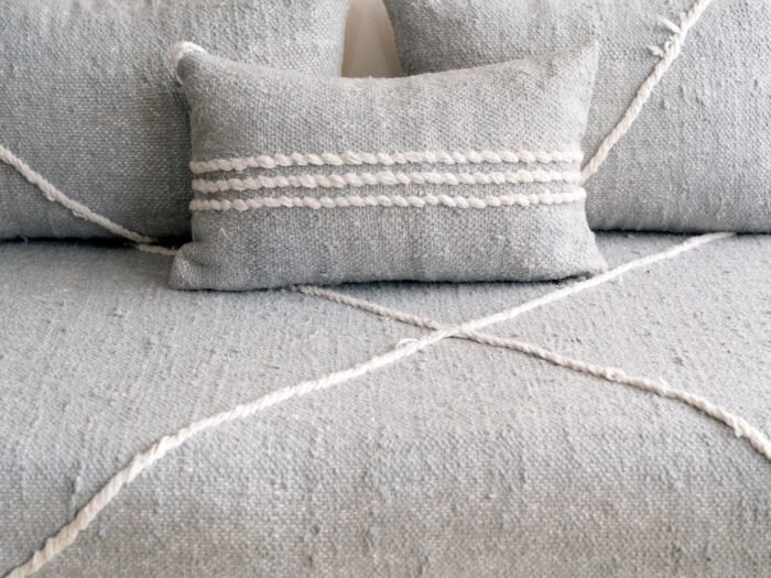 Close-up of handmade light gray cushion covers on Moroccan sofa – minimalist and modern floor couch pillows