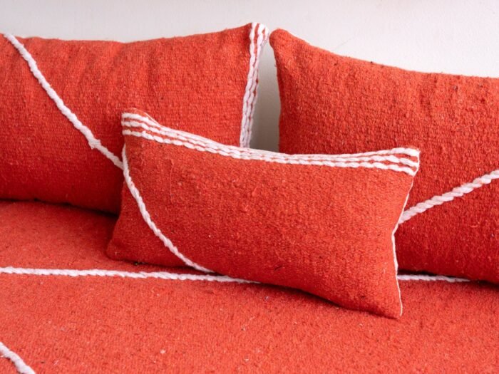 Detail of plain orange pillows on floor sofa – artisan handmade cushions for bold and boho living spaces