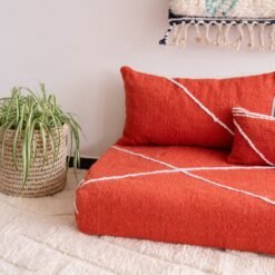 Detail of plain orange pillows on floor sofa – artisan handmade cushions for bold and boho living spaces