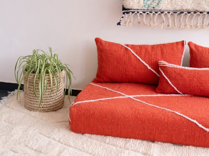Detail of plain orange pillows on floor sofa – artisan handmade cushions for bold and boho living spaces