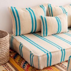 Left side image of Moroccan floor seating with turquoise striped pattern on cream – handmade wool low sofa