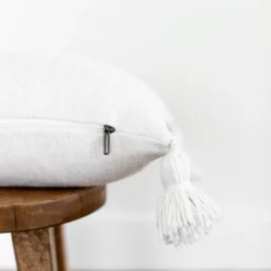 Detailed close-up of cotton pompoms and weave texture on white Moroccan pillow – artisan craftsmanship for soft boho decor