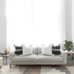 White Moroccan pillows with pompom edges styled in a cozy living room – handwoven cotton cushions for soft, neutral, boho decor