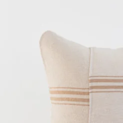 Angled view of a handwoven Moroccan cotton pillow cover in cream white with natural tan stripes – artisan style cushion for modern and bohemian spaces
