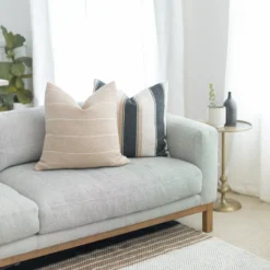 Tan pillows with white stripes styled on a modern neutral couch – handwoven Moroccan cotton cushions for cozy and boho spaces
