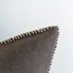 Angled view of a handwoven dark grey Moroccan cushion with thick decorative stitching – side perspective for bohemian, Japandi, or rustic interiors