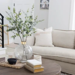 Decorative Moroccan pillow cover styled on a wooden chair – cream-colored cotton with tan stripe detail, blends beautifully with minimalist and neutral décor
