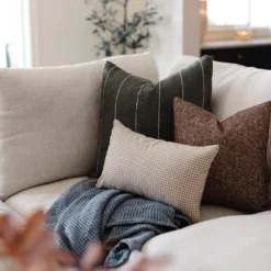 Handwoven Moroccan pillow in moss green with off-white stripes styled in boho interior – natural earthy cotton cushion for relaxed living spaces