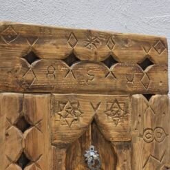 Upper part of handcrafted Moroccan wooden panel featuring geometric Berber carvings and rustic wood finish