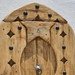 Upper section of arched Moroccan wooden panel showing curved detailing and metal studs