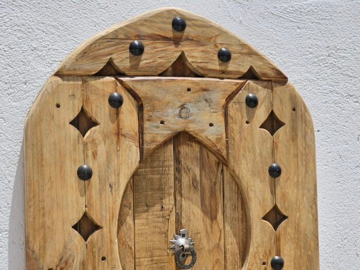 Upper section of arched Moroccan wooden panel showing curved detailing and metal studs