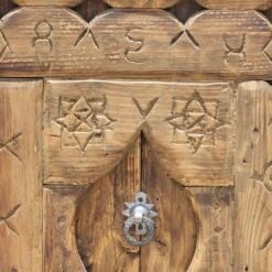 Moroccan wooden wall decor featuring a metal door knocker and detailed star-shaped tribal carvings