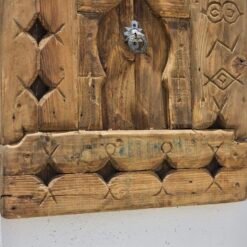 bottom section of a vintage Moroccan wood panel showing aged surface and hand-carved motifs
