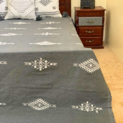 Artisan Moroccan wool blanket in grey with white embroidered patterns – shown with matching handmade pillows