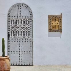 Outdoor installation view of Moroccan shutter beside traditional white door