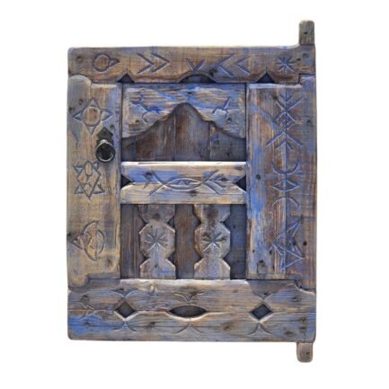 Vintage Moroccan blue shutter window with Berber carvings on white wall