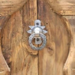 Detailed view of a traditional Moroccan metal door knocker mounted on aged carved wood
