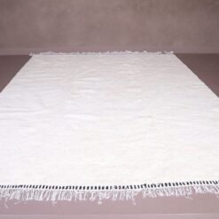 white Moroccan Beni Ourain rug made from 100% natural wool, handwoven by Berber artisans. The image reveals the soft texture and artisan craftsmanship that make this rug a luxurious yet functional statement piece for your home