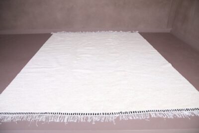 white Moroccan Beni Ourain rug made from 100% natural wool, handwoven by Berber artisans. The image reveals the soft texture and artisan craftsmanship that make this rug a luxurious yet functional statement piece for your home