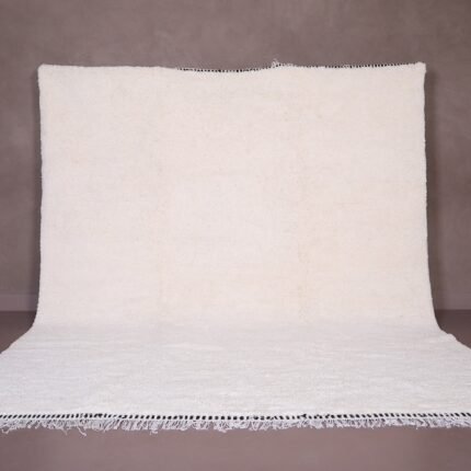 Authentic handmade Moroccan white Beni Ourain rug crafted from 100% natural wool by skilled Berber women artisans. This minimalist solid white wool carpet features a soft texture and timeless elegance, perfect for modern, Scandinavian, or bohemian home interiors. Ideal for living rooms, bedrooms, or wall decor.
