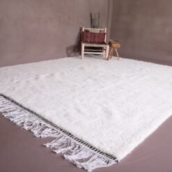 authentic white Moroccan Beni Ourain rug, highlighting the craftsmanship of each knot and the solid white wool weave. This elevated angle gives a closer look at the detail, making it a perfect piece for home décor enthusiasts and interior designers.