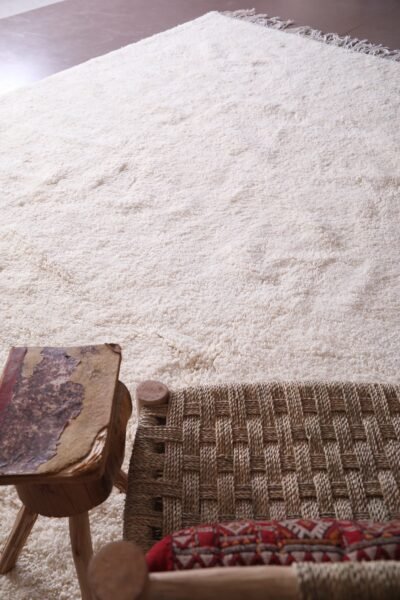 handmade white Moroccan Beni Ourain wool rug, displaying its minimalist design and geometric precision. Perfect as a floor covering or artistic wall hanging, this view emphasizes the rug’s cultural and decorative value