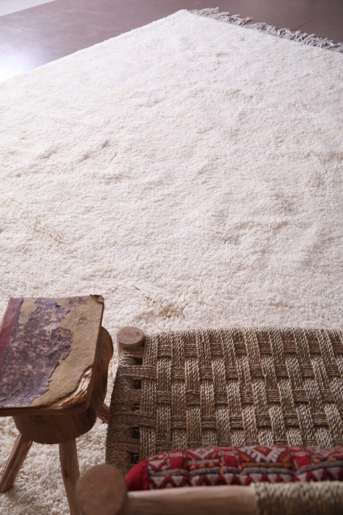 handmade white Moroccan Beni Ourain wool rug, displaying its minimalist design and geometric precision. Perfect as a floor covering or artistic wall hanging, this view emphasizes the rug’s cultural and decorative value