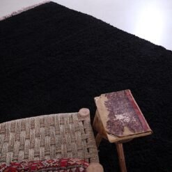 Moroccan Beni Ourain rug in deep black, showing detailed hand-knotting and rich wool texture. This perspective emphasizes the rug’s handcrafted nature and soft, durable weave, ideal for tactile, warm living environments.