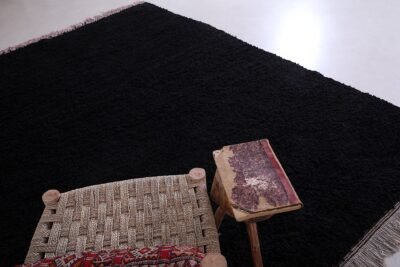 Moroccan Beni Ourain rug in deep black, showing detailed hand-knotting and rich wool texture. This perspective emphasizes the rug’s handcrafted nature and soft, durable weave, ideal for tactile, warm living environments.