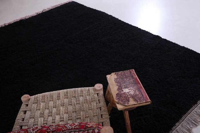 Moroccan Beni Ourain rug in deep black, showing detailed hand-knotting and rich wool texture. This perspective emphasizes the rug’s handcrafted nature and soft, durable weave, ideal for tactile, warm living environments.