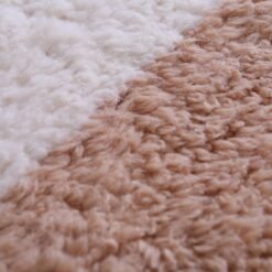 Macro zoom of wool texture on ivory and tan Moroccan rug, displaying natural fiber detail and luxurious density.