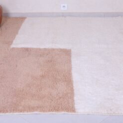 corner of handmade Moroccan rug in ivory and tan, revealing rug thickness and high-quality construction.