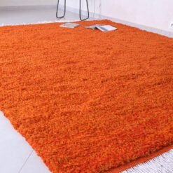 handmade Moroccan wool rug in vibrant rustic orange, featuring authentic Berber tribal designs, natural lamb’s wool material, and finished with traditional fringed tassels.