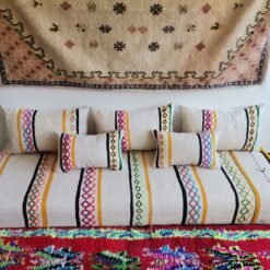 Stacked pillow covers showing colorful embroidery on ivory wool fabric