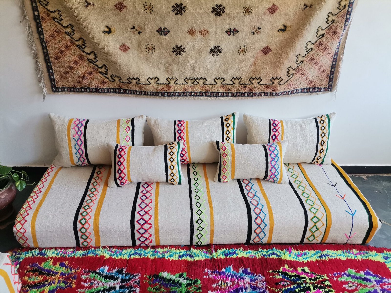 Stacked pillow covers showing colorful embroidery on ivory wool fabric