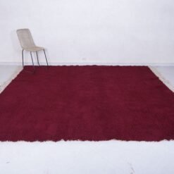 handmade Moroccan burgundy rug with thick wool pile, highlighting the luxurious texture, minimalist elegance, and cultural authenticity of Beni Ourain weaving.