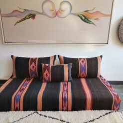 Stacked wool pillow covers in black, orange, and blue embroidery