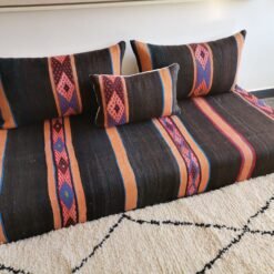 Boho-style room with black and orange Moroccan floor seating with blue stripes