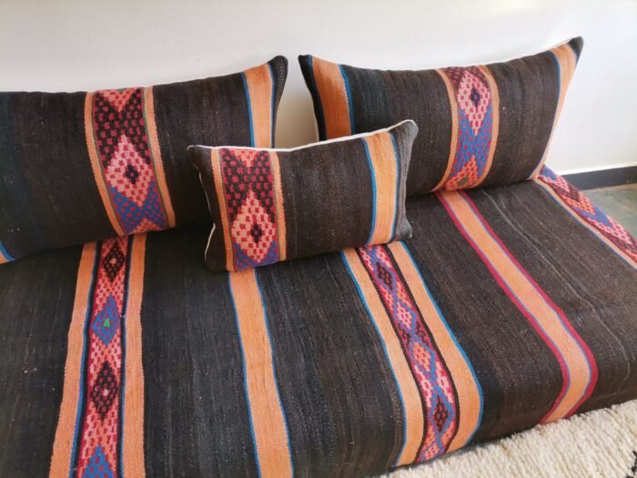 Side view of black and orange Moroccan floor cushion with visible embroidered stripe