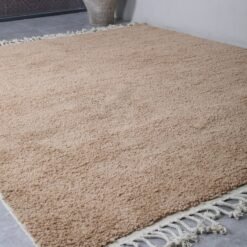 handmade Moroccan rug in sand brown, with clean edges and optional fringe. A perfect solid rug for serene and earthy home design.