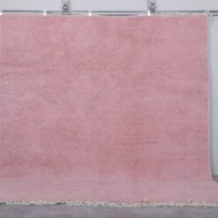 Moroccan millennial pink wool rug, highlighting its hand-knotted texture, soft pastel tone, and thick, plush wool surface made by Berber artisans in Morocco.