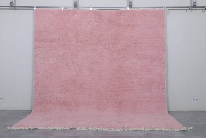 Moroccan millennial pink wool rug, highlighting its hand-knotted texture, soft pastel tone, and thick, plush wool surface made by Berber artisans in Morocco.