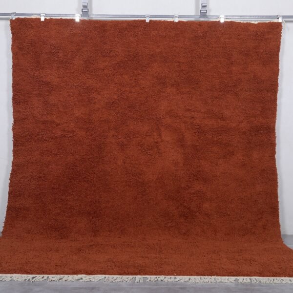 Handmade Moroccan warm terracotta wool rug in solid color, crafted by Berber artisans using 100% natural lamb wool, perfect for boho, rustic, and modern interiors with a cozy, earthy aesthetic.