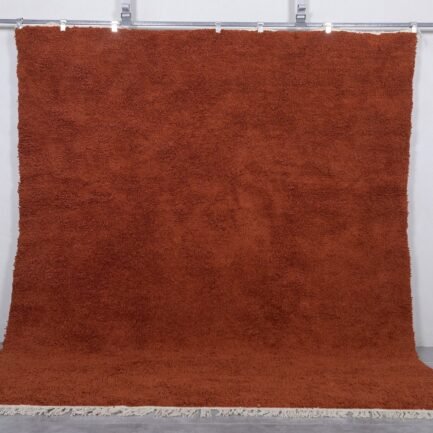 Handmade Moroccan warm terracotta wool rug in solid color, crafted by Berber artisans using 100% natural lamb wool, perfect for boho, rustic, and modern interiors with a cozy, earthy aesthetic.