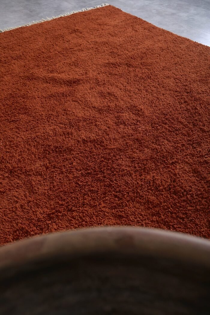 solid warm terracotta Moroccan wool rug, highlighting its dense pile and minimalist design, handmade with natural lamb wool for lasting durability.