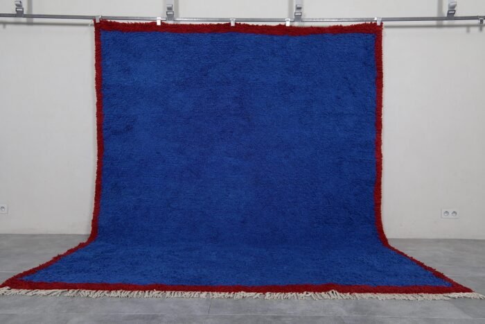 Authentic Moroccan Blue Beni Ourain rug hand-knotted by skilled Berber women artisans using 100% natural sheep wool. This striking wool carpet features a deep, vibrant blue color inspired by the Mediterranean Sea and Atlantic Ocean. Its traditional Berber design and luxurious texture make it perfect for enhancing living rooms, bedrooms, or walls with cultural and artistic elegance.