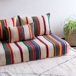 Moroccan floor seating arrangement with ivory lamb wool cushions and vibrant stripes