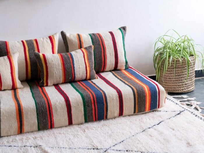 Moroccan floor seating arrangement with ivory lamb wool cushions and vibrant stripes